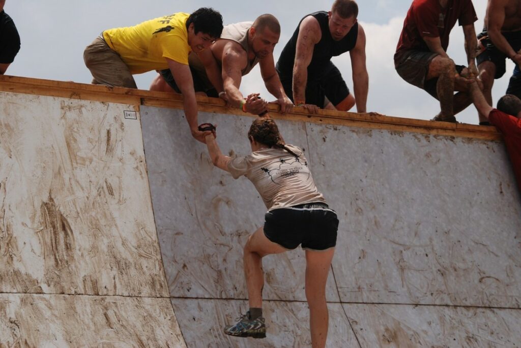 Three guys helping a girl climb up